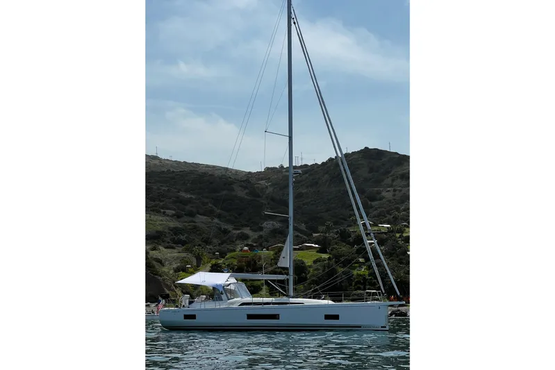  Yacht Photos Pics 2023 Beneteau Oceanis 46.1 sailboat on calm water with scenic hillside backdrop.