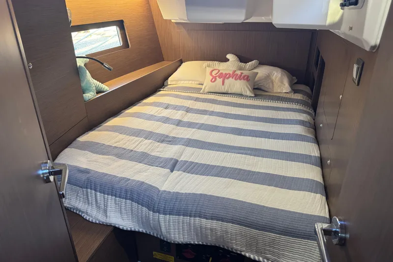  Yacht Photos Pics Cozy cabin interior of 2023 Beneteau Oceanis 46.1 with striped bedding and personalized pillow.