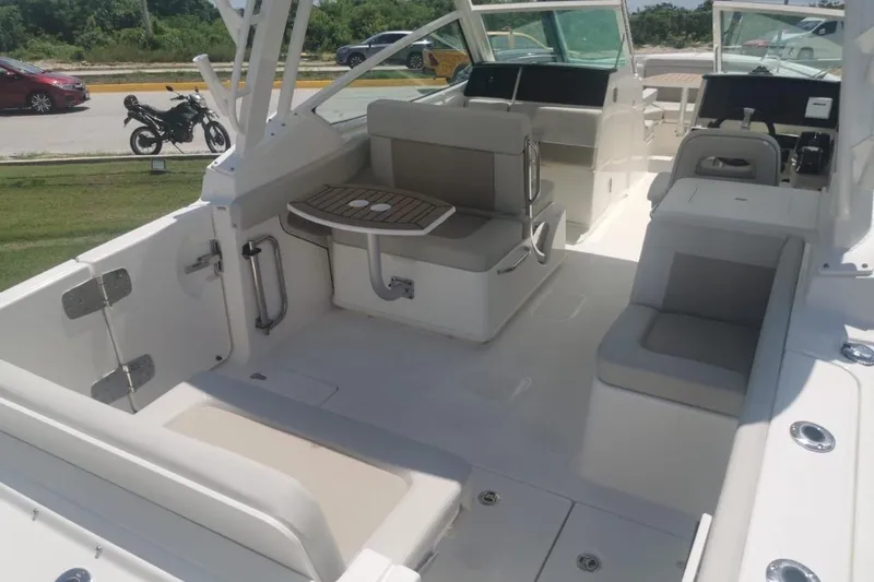 Casa - 2023 Bw 280 Vnt Yacht Photos Pics 2023 Boston Whaler 280 Vantage boat interior with seating and table, parked outdoors.