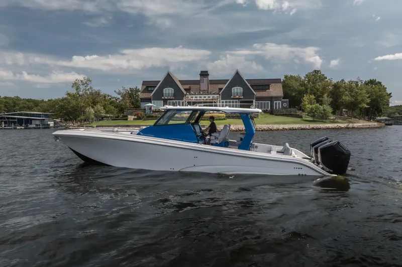  Yacht Photos Pics 2026 Fountain 43 SCX boat cruising on a lake near a large house.