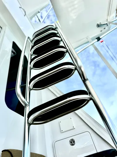 Red Queen Yacht Photos Pics Stainless steel ladder on 2008 Hatteras Enclosed Bridge yacht against blue sky.