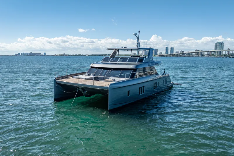 Skip The Wait Yacht Photos Pics 2026 Sunreef 60 Power yacht on calm waters with city skyline in background.