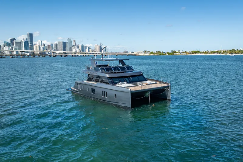 Skip The Wait Yacht Photos Pics 2026 Sunreef 60 Power yacht cruising near city skyline on a sunny day.
