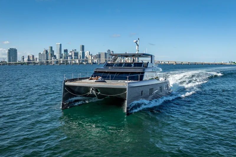 Skip The Wait Yacht Photos Pics 2026 Sunreef 60 Power yacht cruising near city skyline on a sunny day.