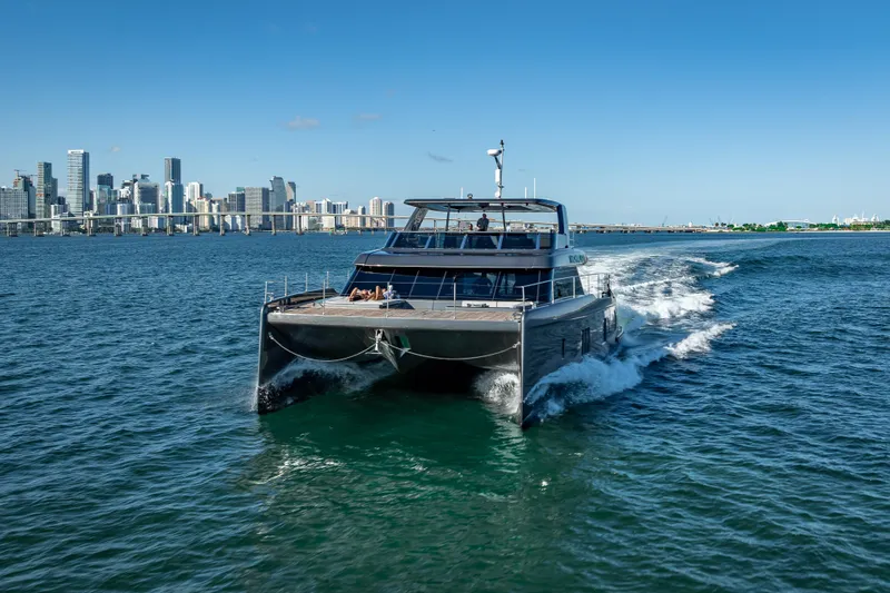 Skip The Wait Yacht Photos Pics 2026 Sunreef 60 Power yacht cruising near city skyline on a sunny day.