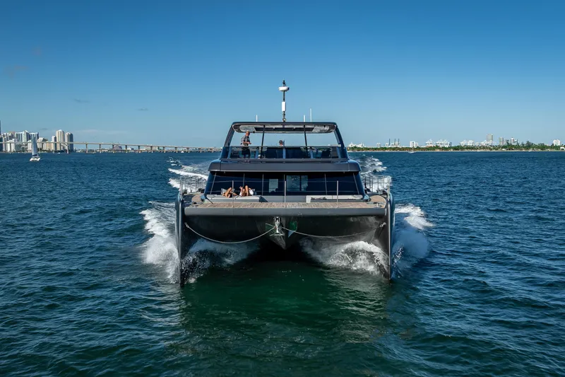 Skip The Wait Yacht Photos Pics 2026 Sunreef 60 Power yacht cruising on open water with city skyline in background.