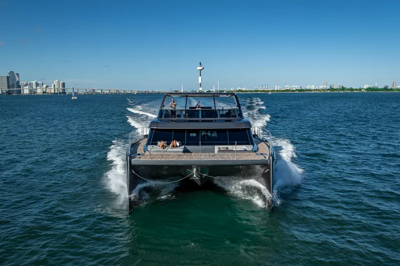 Skip The Wait Yacht Photos Pics 2026 Sunreef 60 Power yacht cruising on open water with city skyline backdrop.
