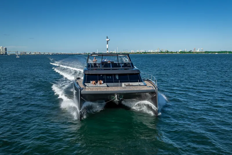 Skip The Wait Yacht Photos Pics 2026 Sunreef 60 Power yacht cruising on open water, city skyline in background.