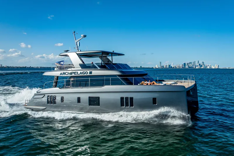 Skip The Wait Yacht Photos Pics 2026 Sunreef 60 Power yacht cruising on open water with city skyline in background.