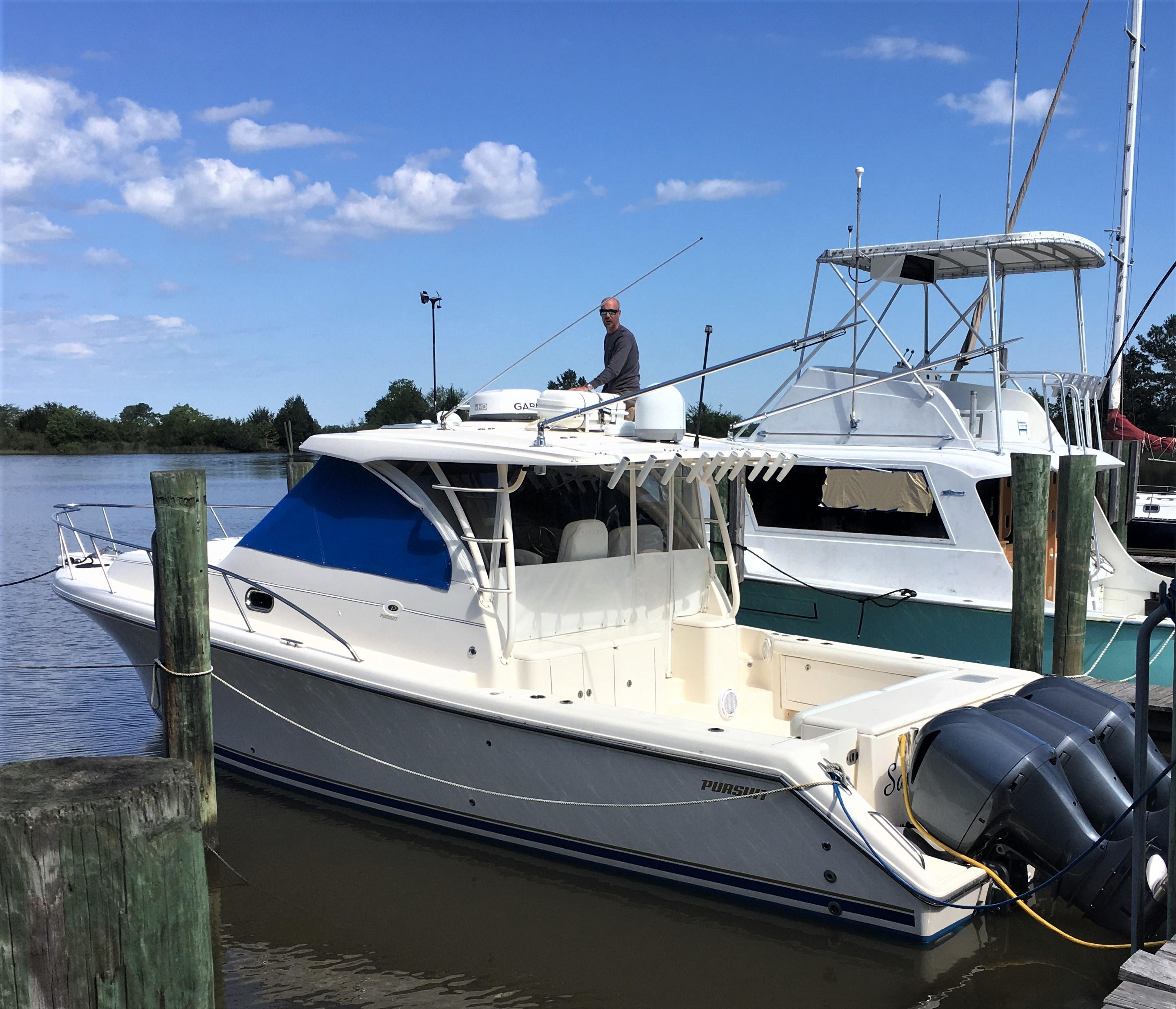 2013 Pursuit OS 385 Offshore boat docked at a marina on a sunny day.
