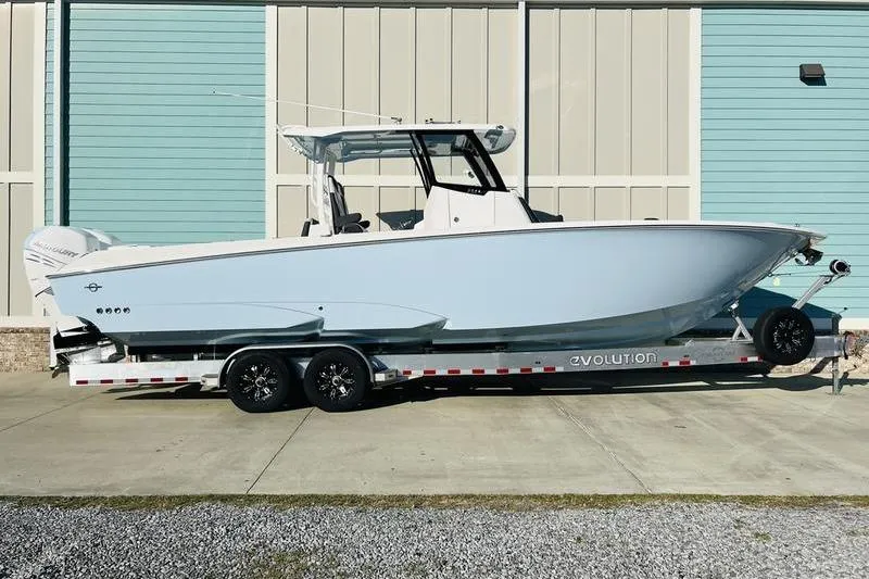  Yacht Photos Pics 2023 Fountain 32 NX boat on trailer, parked outdoors against a blue building.
