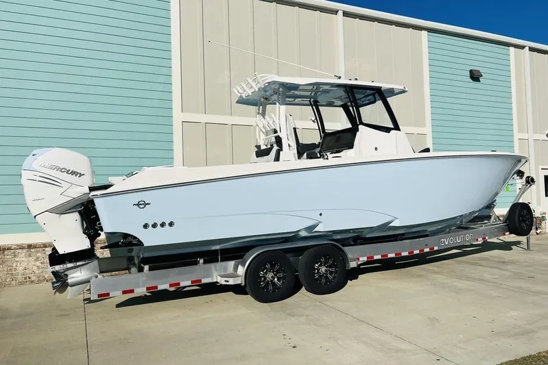  Yacht Photos Pics 2023 Fountain 32 NX boat on trailer, parked near a light blue building.