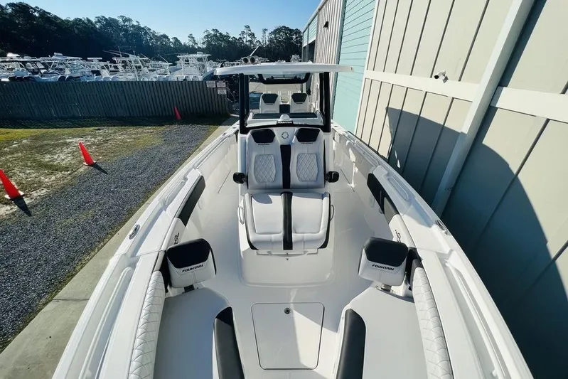  Yacht Photos Pics 2023 Fountain 32 NX boat with sleek white interior and seating, docked outdoors.