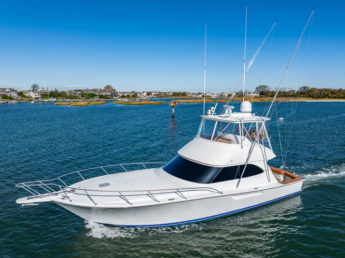 Amore Mia Yacht Photos Pics 2015 Viking 46 Convertible yacht cruising on a sunny day, near a coastal town.