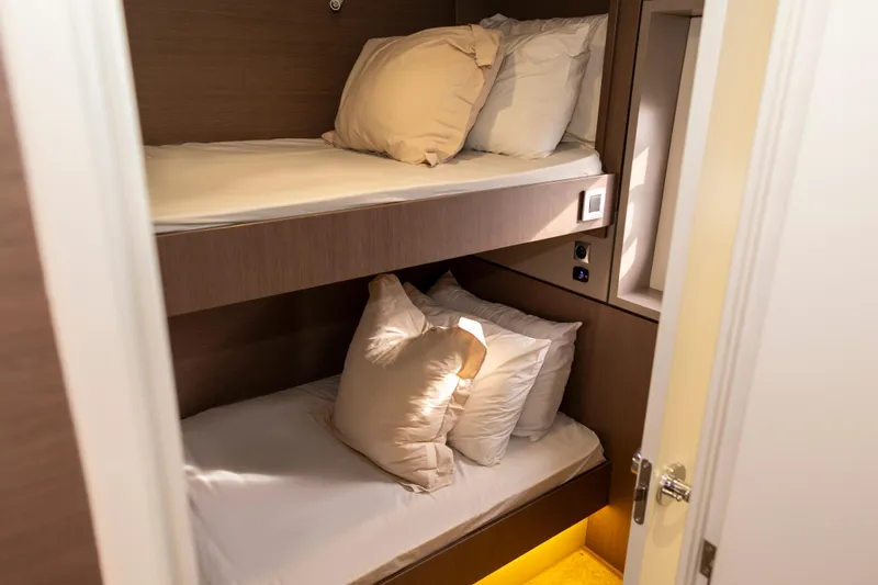 Tatani Yacht Photos Pics Bunk beds in a 2021 Bali 4.8 yacht cabin, featuring cozy pillows and warm lighting.