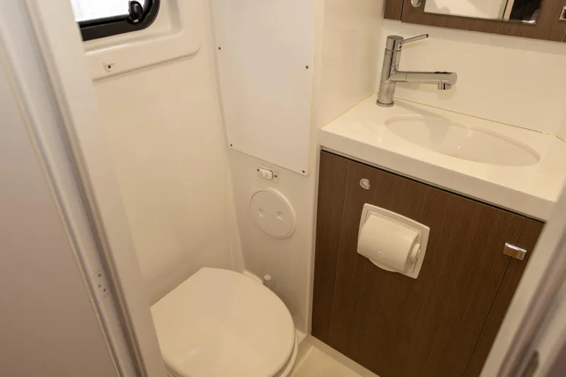Tatani Yacht Photos Pics Compact bathroom in a 2021 Bali 4.8, featuring a toilet, sink, and wooden cabinetry.