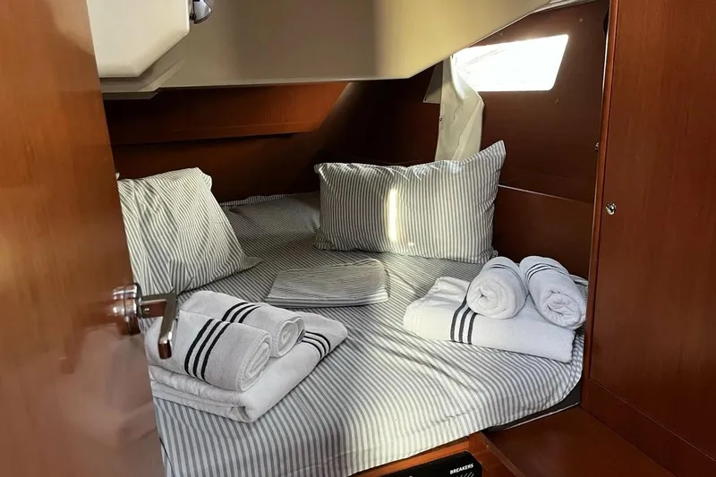  Yacht Photos Pics Cozy cabin interior of 2017 Beneteau Oceanis 41.1 with striped bedding and towels.