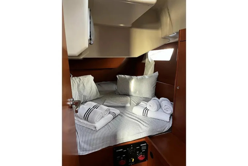  Yacht Photos Pics Cozy cabin interior of 2017 Beneteau Oceanis 41.1 with striped bedding and rolled towels.