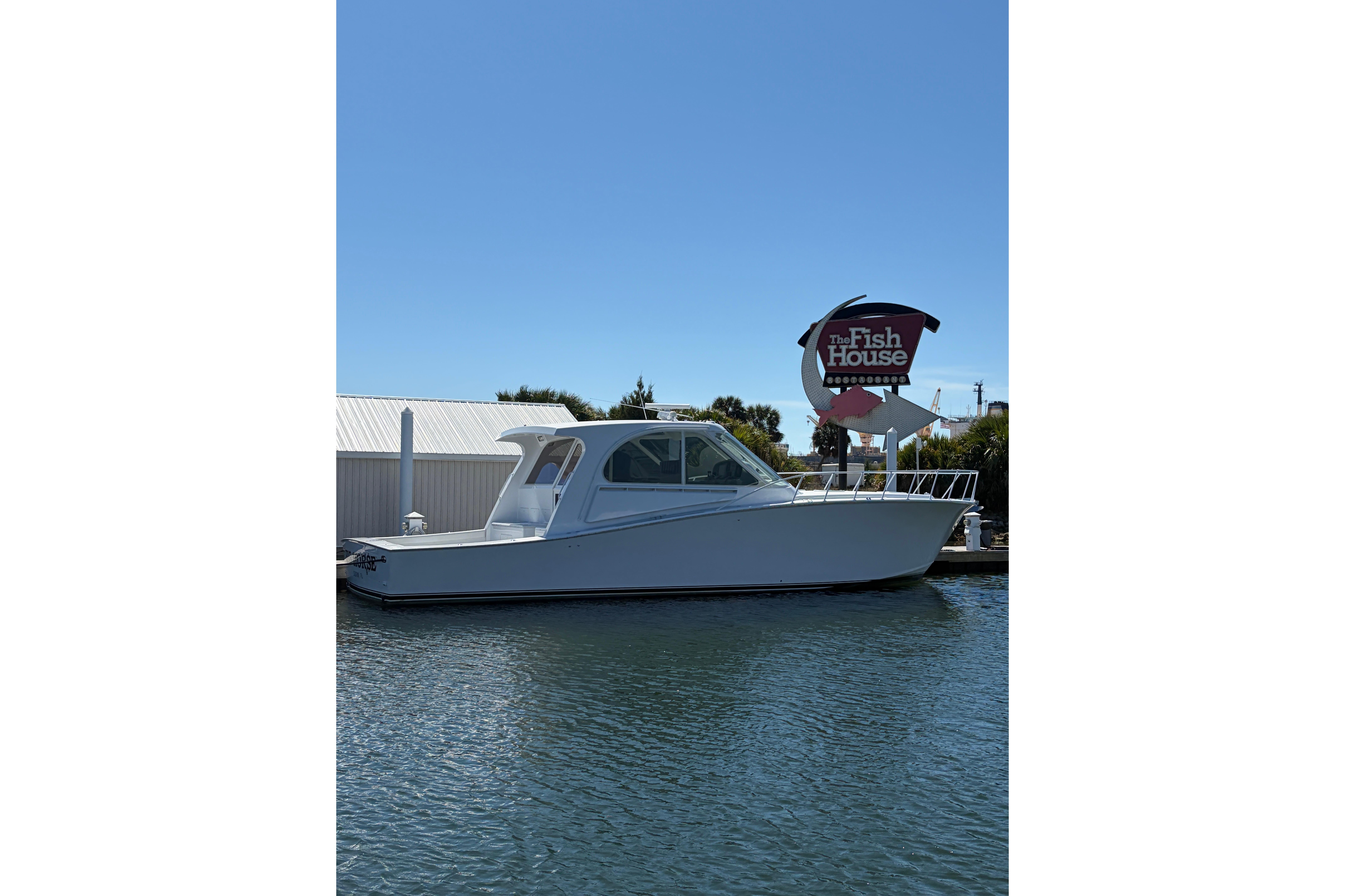 White 2006 Dixon 52 boat docked near "The Fish House" sign on a sunny day.