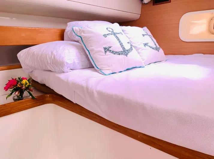Una Vida Yacht Photos Pics Cozy cabin bed in 2004 Leopard 47 yacht with anchor-themed pillows and fresh flowers.