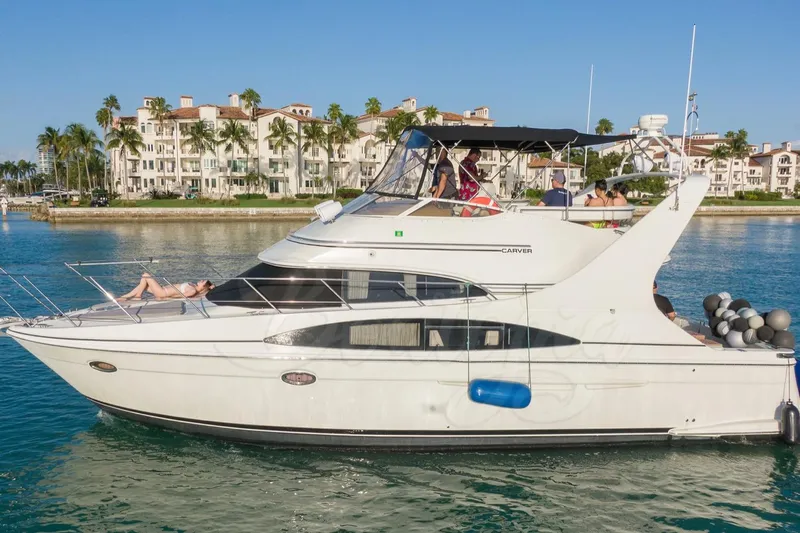  Yacht Photos Pics 2004 Carver 420 Mariner yacht cruising near waterfront buildings and palm trees.