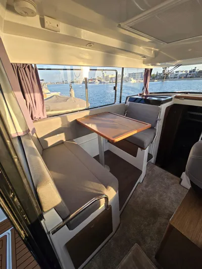 Down Time Yacht Photos Pics 2020 Jeanneau NC 895 Sport interior with seating and table, overlooking water.