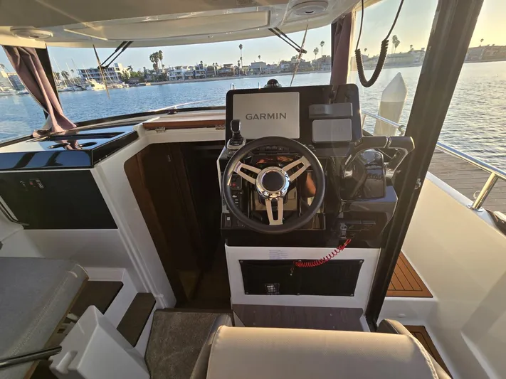 Down Time Yacht Photos Pics 2020 Jeanneau NC 895 Sport helm with Garmin navigation, overlooking serene waterfront.