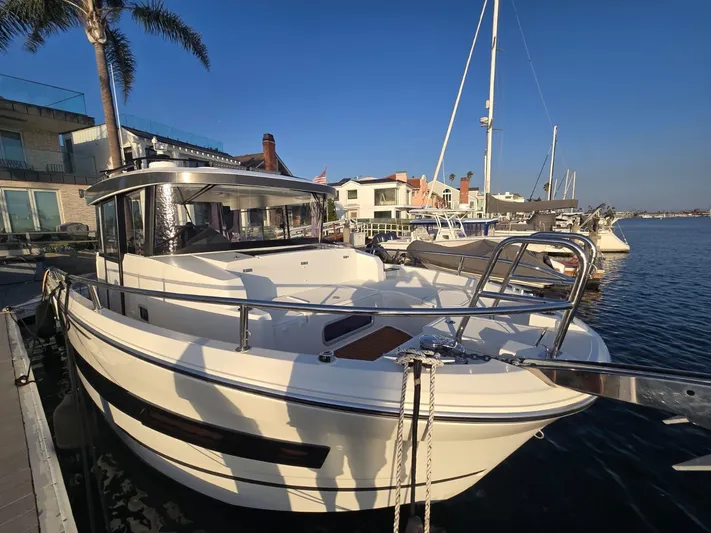 Down Time Yacht Photos Pics 2020 Jeanneau NC 895 Sport boat docked at marina, clear sky, waterfront homes in background.