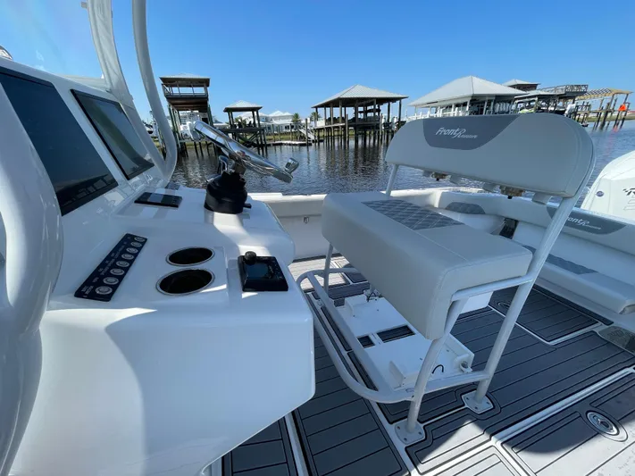Motivated Yacht Photos Pics 2023 Front Runner 26 Center Console boat interior with helm and seating, docked by waterfront.