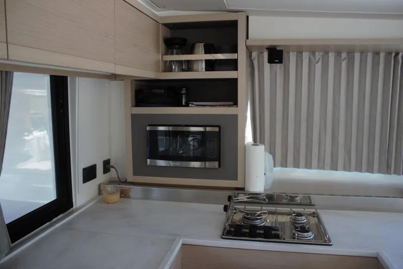 Jungle Goddess Yacht Photos Pics Modern kitchen interior of 2022 Lagoon 46 yacht with stove and microwave.