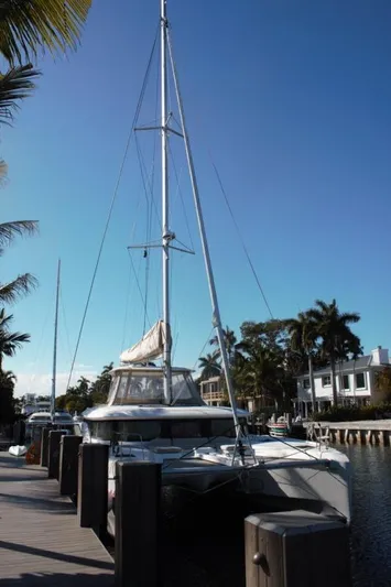 Jungle Goddess Yacht Photos Pics 2022 Lagoon 46 catamaran docked by palm trees under clear blue sky.
