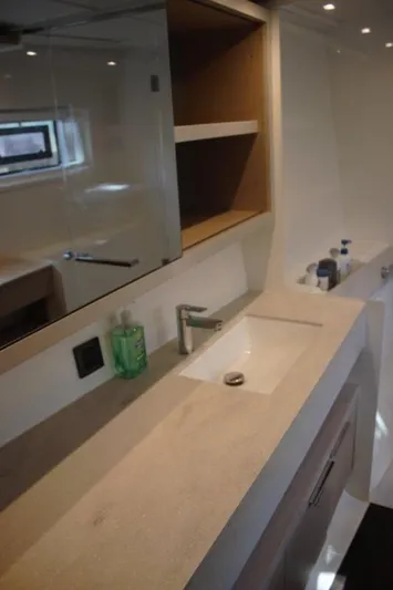 Jungle Goddess Yacht Photos Pics Modern bathroom interior in 2022 Lagoon 46 yacht, featuring sleek sink and mirror.