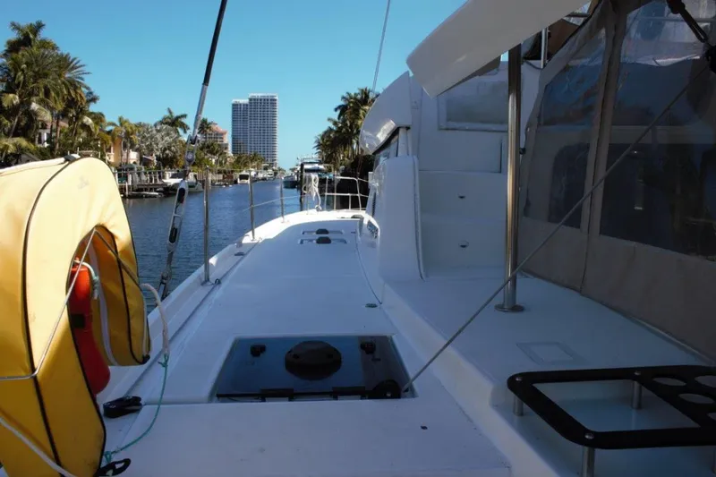 Jungle Goddess Yacht Photos Pics 2022 Lagoon 46 catamaran docked in a scenic canal with palm trees and buildings.