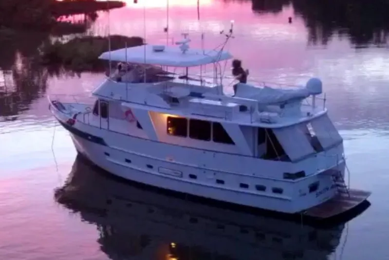 Noelani Yacht Photos Pics 1982 DeFever 52 Offshore Cruiser on serene water at sunset.