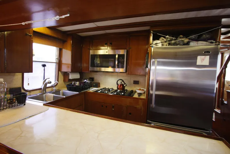 Noelani Yacht Photos Pics 1982 DeFever 52 Offshore Cruiser kitchen with stainless steel appliances and wooden cabinetry.