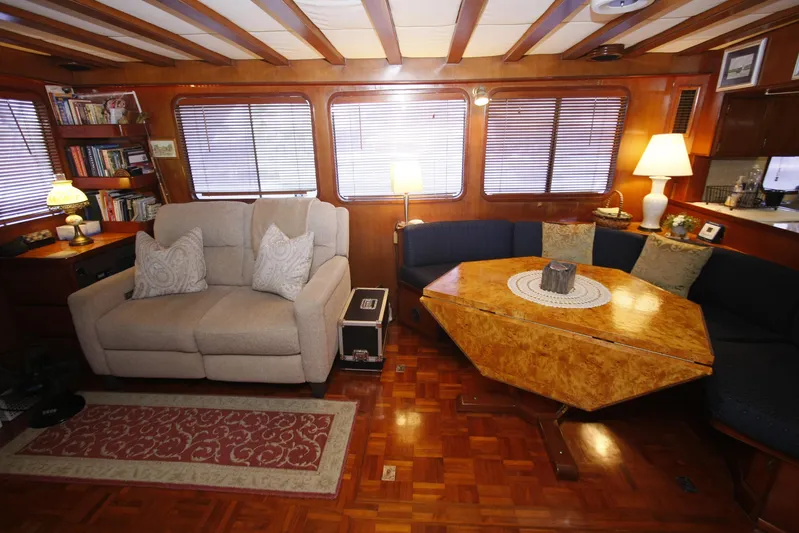 Noelani Yacht Photos Pics Cozy interior of 1982 DeFever 52 Offshore Cruiser with sofa, table, and bookshelves.