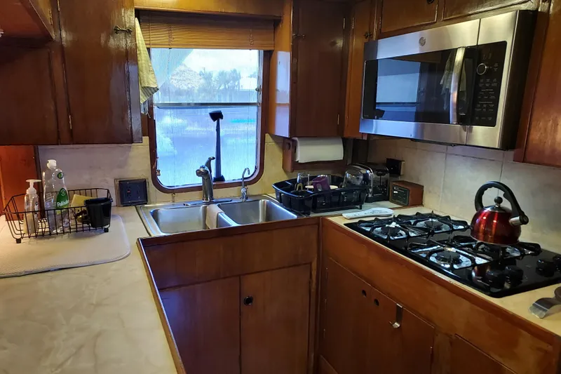 Noelani Yacht Photos Pics 1982 DeFever 52 Offshore Cruiser kitchen with wooden cabinets, stove, and microwave.