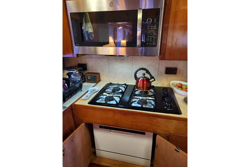 Noelani Yacht Photos Pics Galley kitchen in 1982 DeFever 52 Offshore Cruiser with stove, microwave, and kettle.