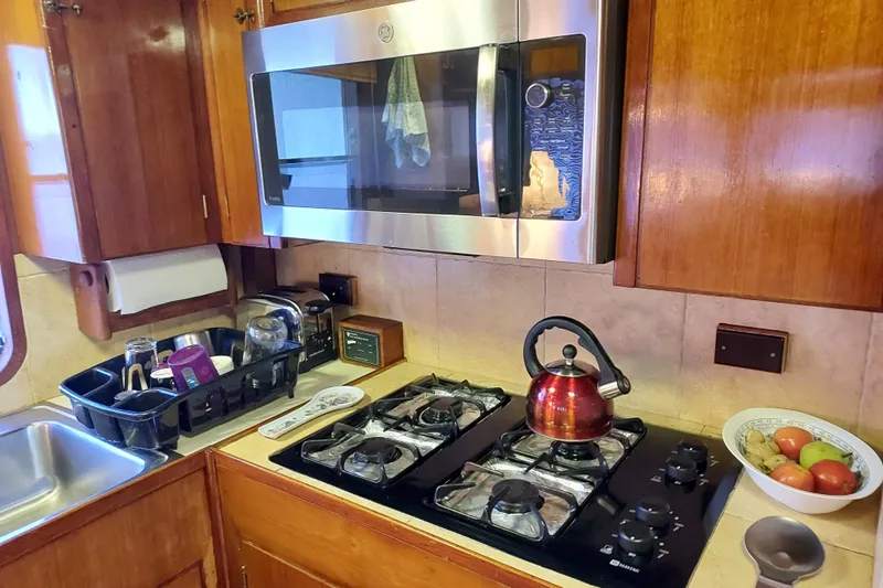 Noelani Yacht Photos Pics Galley kitchen in 1982 DeFever 52 Offshore Cruiser with stove, microwave, and sink.