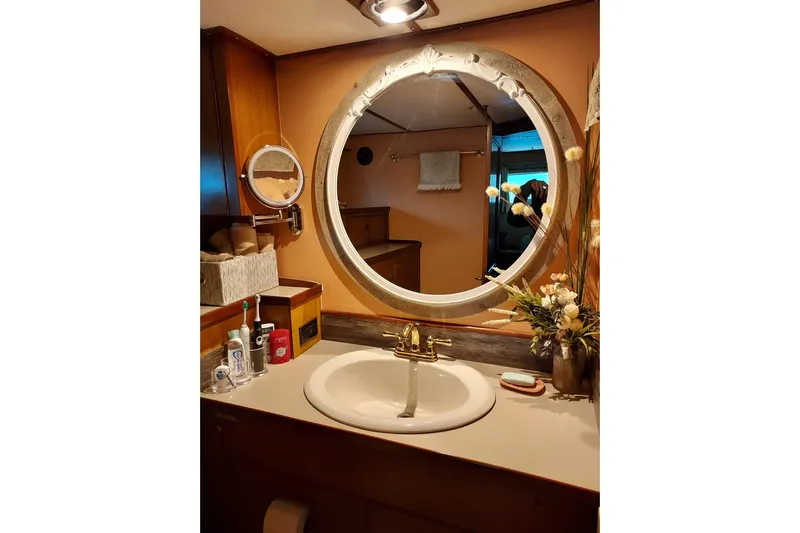 Noelani Yacht Photos Pics Elegant bathroom on 1982 DeFever 52 Offshore Cruiser with round mirror and floral decor.