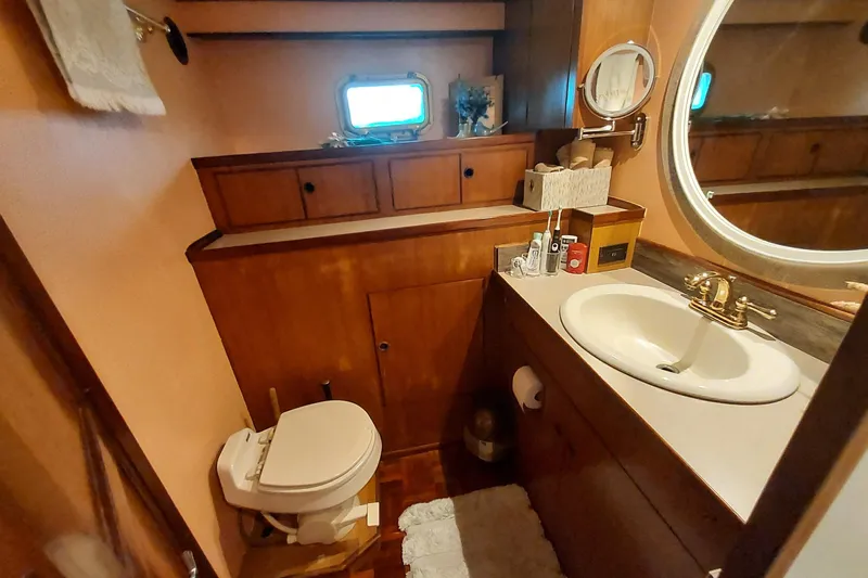 Noelani Yacht Photos Pics 1982 DeFever 52 Offshore Cruiser bathroom with wooden cabinetry and oval mirror.