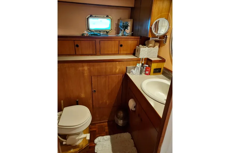 Noelani Yacht Photos Pics 1982 DeFever 52 Offshore Cruiser bathroom with wooden cabinetry and porthole window.