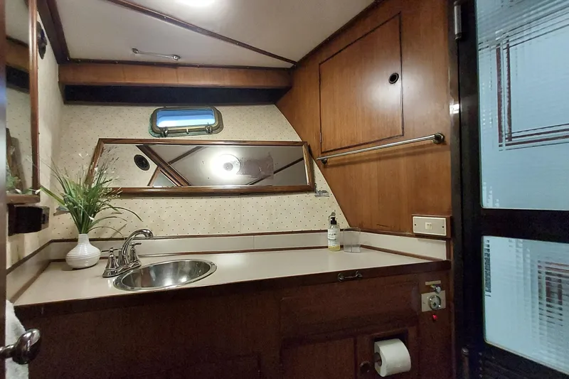 Noelani Yacht Photos Pics 1982 DeFever 52 Offshore Cruiser bathroom with wood paneling and stainless steel sink.