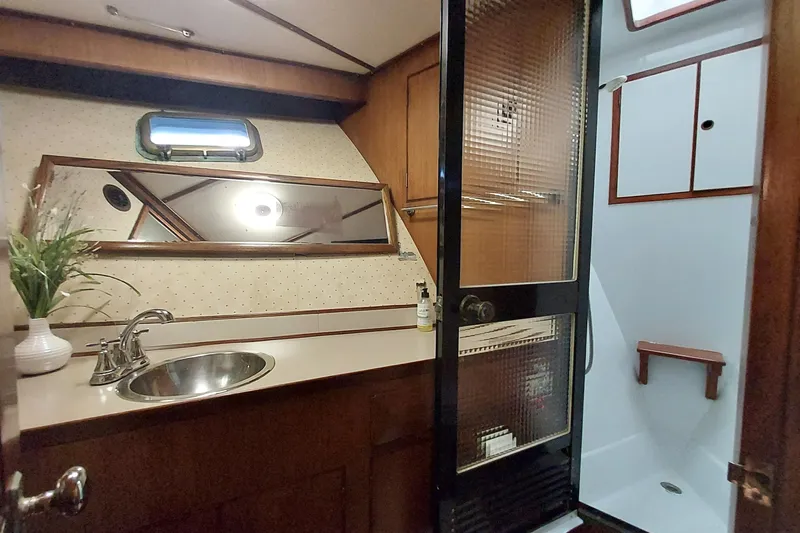 Noelani Yacht Photos Pics 1982 DeFever 52 Offshore Cruiser bathroom with sink, mirror, and shower.