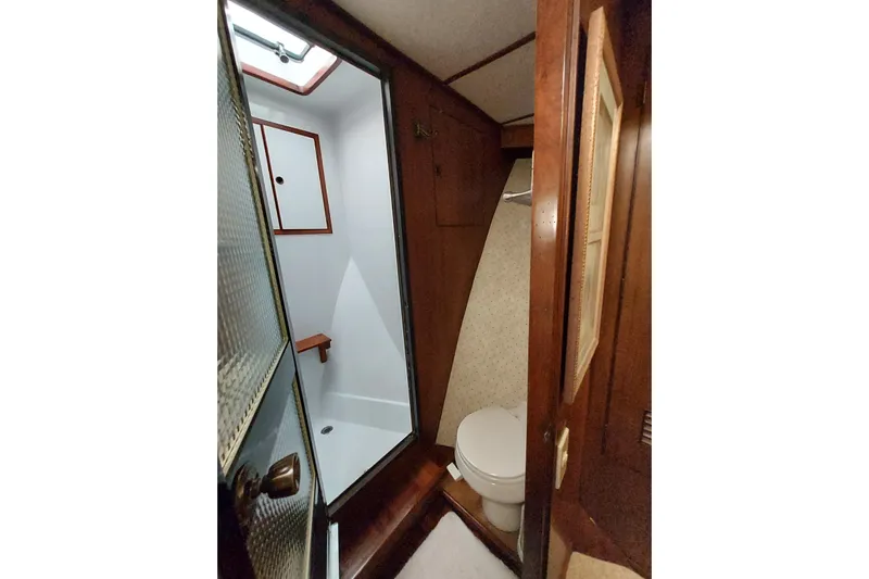 Noelani Yacht Photos Pics 1982 DeFever 52 Offshore Cruiser bathroom with shower and toilet, featuring wooden accents.