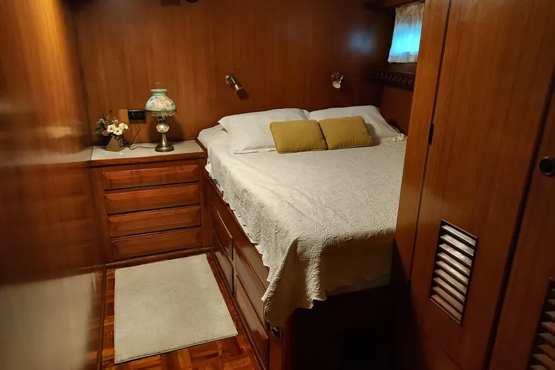 Noelani Yacht Photos Pics Cozy bedroom interior of 1982 DeFever 52 Offshore Cruiser with wood paneling and elegant decor.