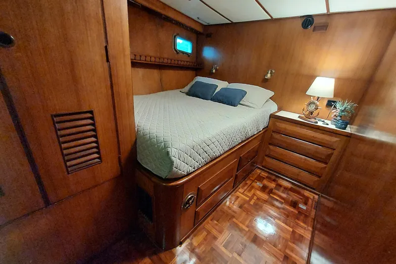 Noelani Yacht Photos Pics 1982 DeFever 52 Offshore Cruiser cabin with wooden interior, cozy bed, and ambient lighting.