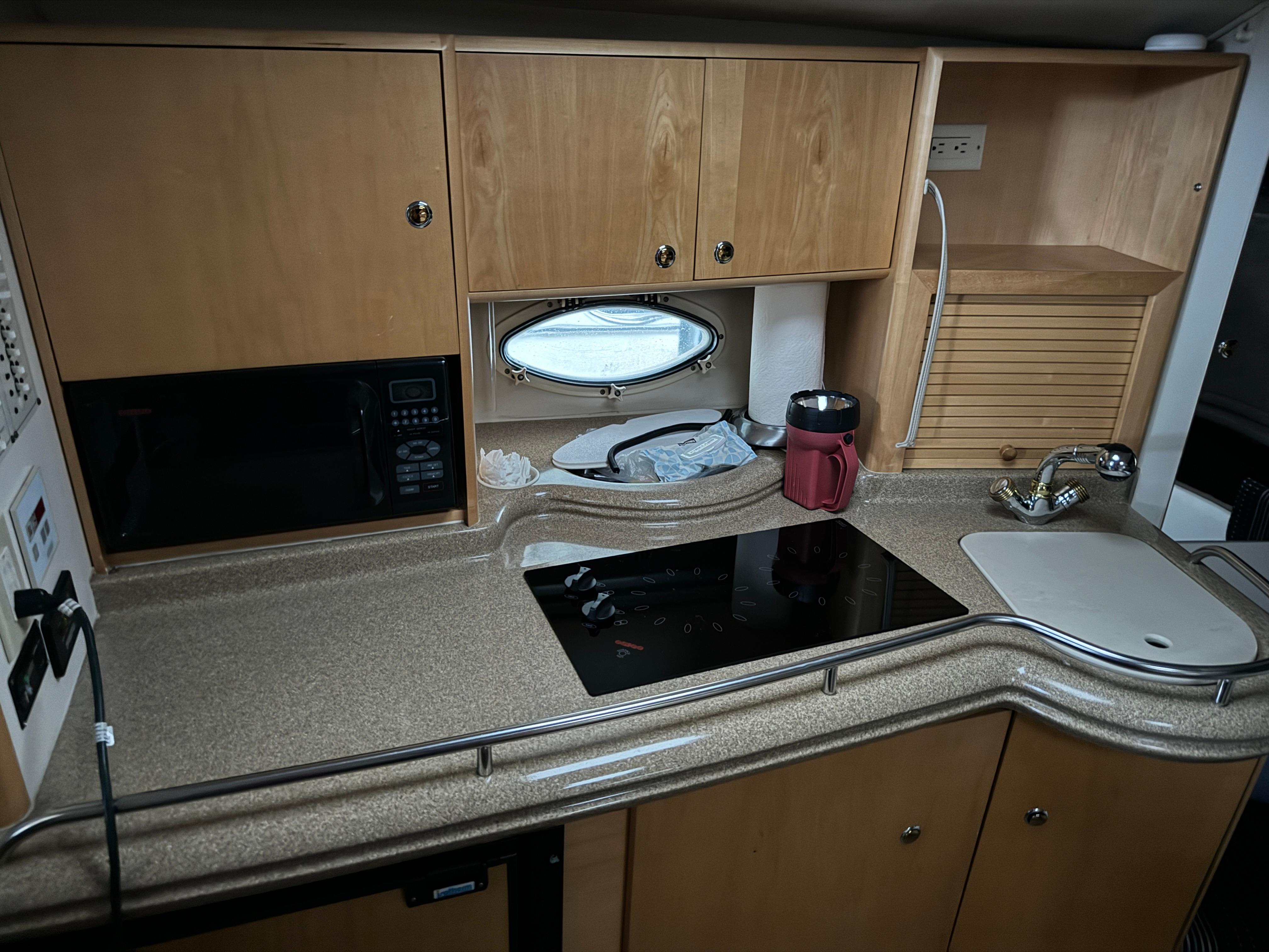 2003 Larson 330 CABRIO kitchen with microwave, stove, sink, and wooden cabinets.