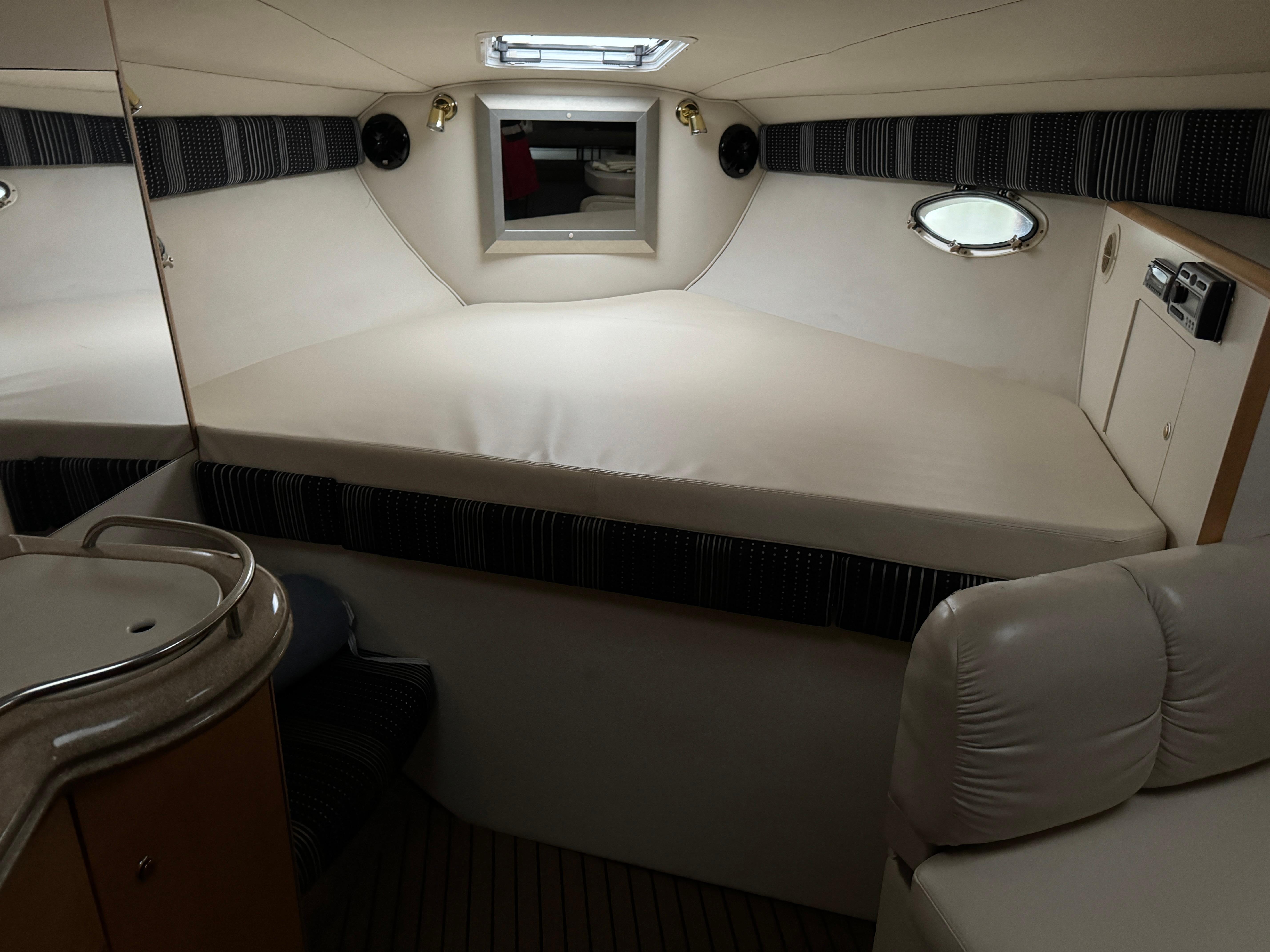 2003 Larson 330 CABRIO cabin interior with bed, sink, and seating area.