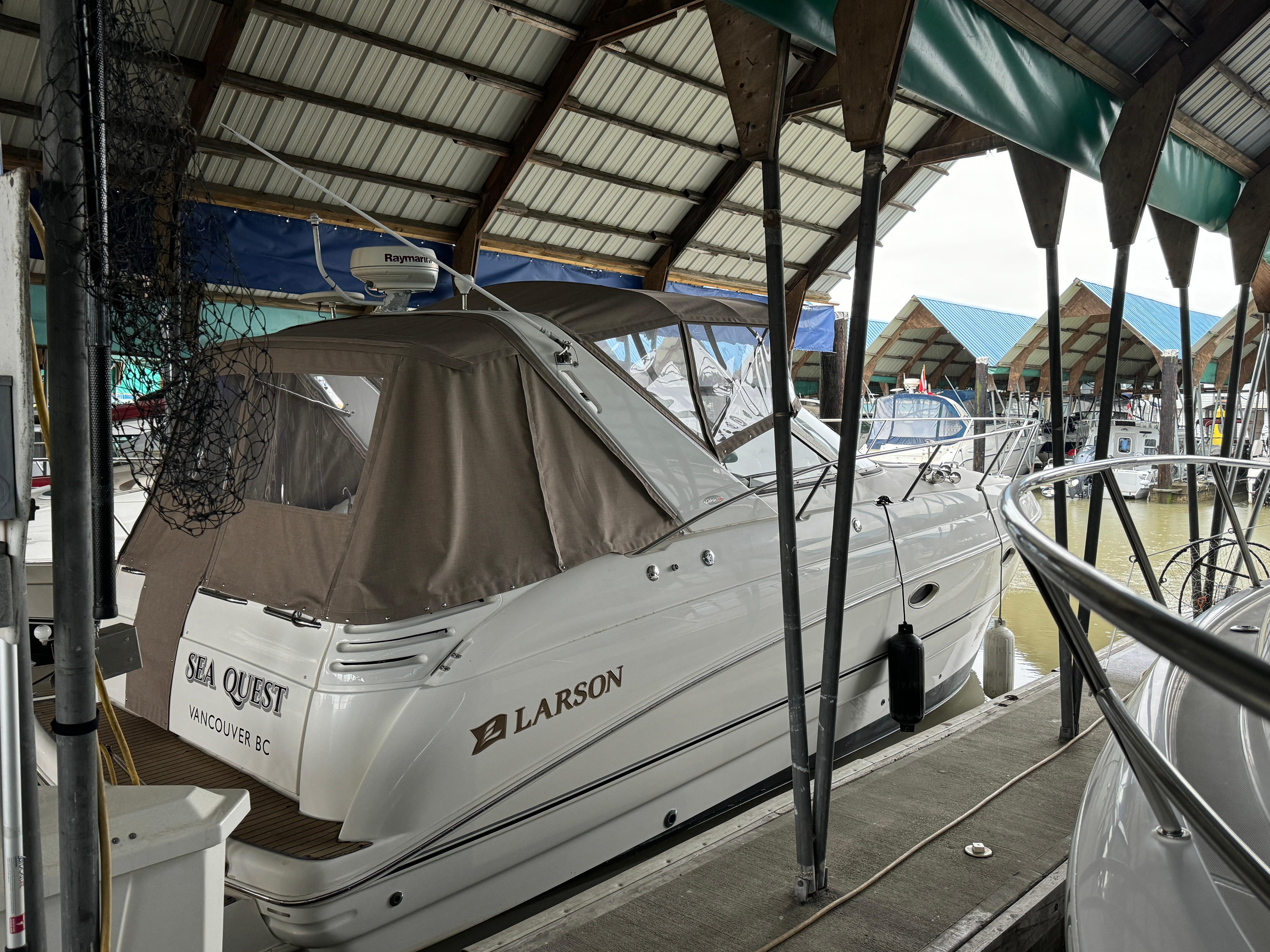 2003 Larson 330 Cabrio boat docked under a covered marina.